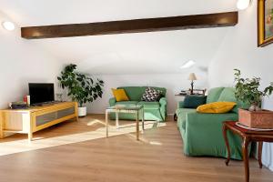 a living room with a green couch and a tv at The View in Levico Terme