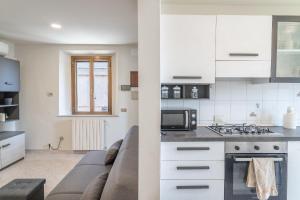 a kitchen and a living room with a couch at La Corte Rurale con jacuzzi in Lucca
