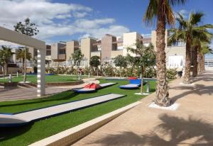 a building with palm trees and someogie boards on the grass at Fantastic apartment in Torrevieja