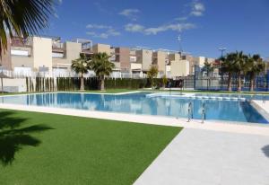 a large swimming pool with green grass in front of a building at Fantastic apartment in Torrevieja