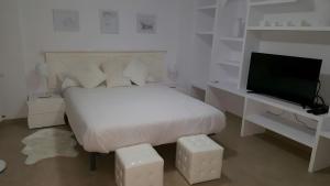 a white bedroom with a bed and a flat screen tv at Casa las Columnas in Capdepera +18 photos