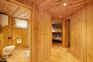 a bathroom with wooden walls and a toilet and a bedroom at Bungalow 19 - Finnhütte in Niesky +12 photos