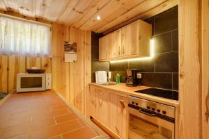 a kitchen with wooden cabinets and a stove and a microwave at Bungalow 19 - Finnhütte in Niesky