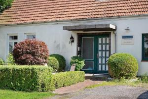 a white house with a green door and bushes at Harmonie Wohnung in Oyten
