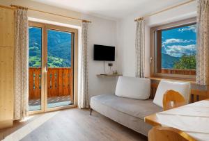 a living room with a couch and a large window at Oberhemberger Hof Feldthurns in Feldthurns