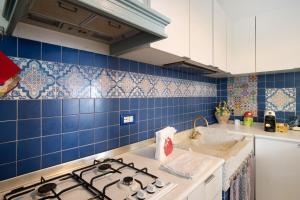a kitchen with a stove and a blue tiled wall at Oasi in Alassio +21 photos