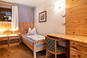 a room with a bed and a desk and a sink at La Plates App Domesdi in Ortisei