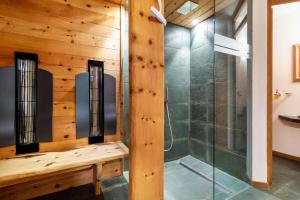 a shower in a bathroom with a wooden wall at La Plates App Domesdi in Ortisei