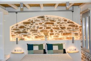 a bedroom with a bed and a stone wall at Celini Villas Tinos in Tinos +72 photos