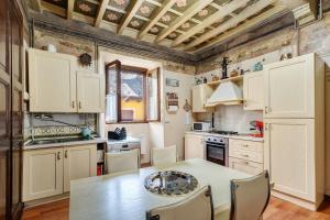a kitchen with white cabinets and a table with chairs at Antro Di Circe - Orta Centro in Orta San Giulio
