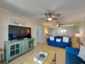 a living room with a blue couch and a flat screen tv at Regency Towers #802 East in Pensacola Beach