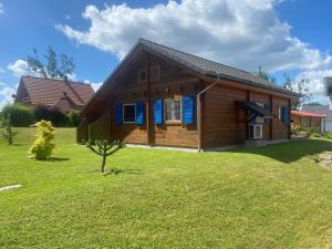 a log cabin with blue shutters on a yard at Ferienhaus Gross Nemerow in Groß Nemerow