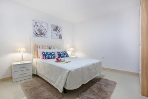 a white bedroom with a white bed with blue pillows at Los Abuelos 2 Icod in Icod de los Vinos