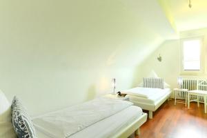 a white bedroom with two beds and a window at Dinkelbach Landhaus 1 B in Lindau-Bodolz