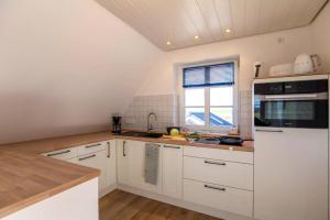 a kitchen with white cabinets and a window at Urlaub an der Nordermühle in Pellworm