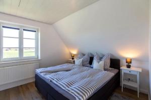 a bedroom with a bed with two night stands and a window at Urlaub an der Nordermühle in Pellworm