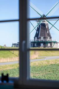 a view of a windmill from a window at Urlaub an der Nordermühle in Pellworm