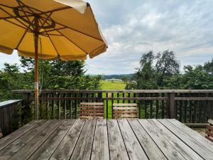 a wooden table with an umbrella on a deck at Hof Sinnenberg in Deggenhausertal