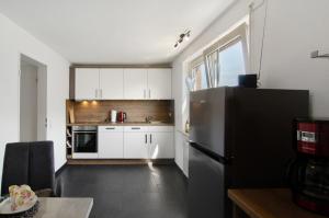a kitchen with white cabinets and a black refrigerator at Ferienwohnung Goesmann in Zetel
