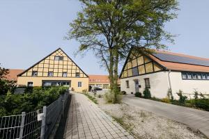 zwei Gebäude mit einem Baum neben einem Gehweg in der Unterkunft Fewo-Romuli in Eggesin