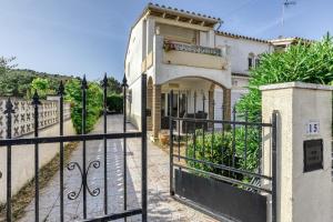 a gate in front of a white house with a balcony at Casa 3 Dormitorios Con Piscina in L'Escala