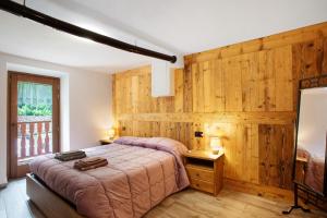 a bedroom with a bed with a wooden wall at Les Cles - Achillea in Valsavarenche