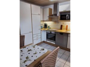 a kitchen with white cabinets and a table and chairs at Mayntz' Albjuwel in Meßstetten