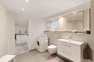 a white bathroom with a washing machine and a sink at Hochwertige Ferienwohnung Ötigheim in Ötigheim +16 photos
