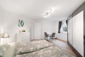 a white bedroom with a bed and a table at Hochwertige Ferienwohnung Ötigheim in Ötigheim