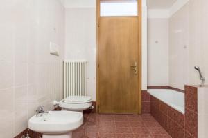 a bathroom with a toilet and a wooden door at Appartamento dorsino in Dorsino +21 photos