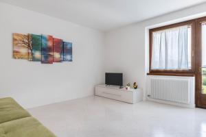 a white living room with a tv and a couch at Appartamento dorsino in Dorsino