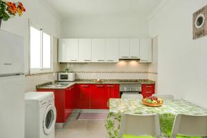 a kitchen with red cabinets and a table with a bowl of fruit at 2a Francesca in Vecindario