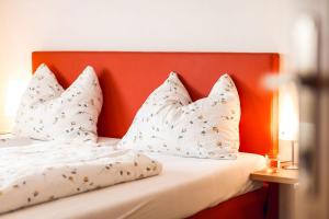 a bed with white pillows and an orange headboard at Ferienwohnung Lanz 3 in Lana