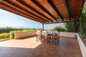 a patio with a table and chairs under a wooden pergola at Villa Zagara in Partinico