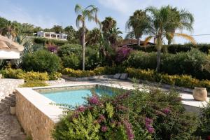 a swimming pool in a garden with flowers and palm trees at Villa Zagara in Partinico