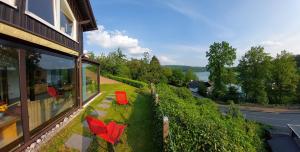 a house with red chairs and a view of the water at Panoramaferienhaus Sorpesee, 120qm in Sundern