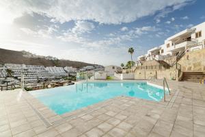 a large swimming pool in a resort with buildings at Bungalow Flores with view in Puerto Rico de Gran Canaria