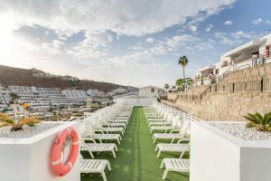 a row of white chairs on the roof of a resort at Bungalow Flores with view in Puerto Rico de Gran Canaria
