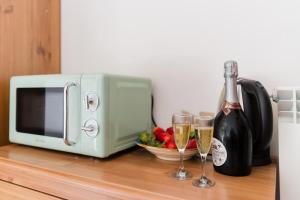 two glasses of champagne next to a microwave and a bottle of wine at Andromeda's Rooms in Otranto
