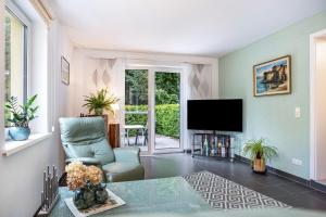 a living room with a television and a chair at Prerow Am Deich - Ferienwohnung 1 in Prerow