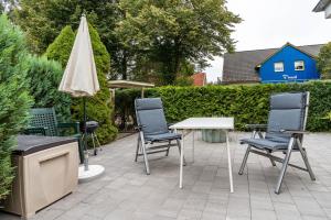 a patio with chairs and a table and an umbrella at Prerow Am Deich - Ferienwohnung 1 in Prerow