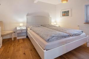 a bedroom with a white bed and a night stand at Ferienwohnungen in Neufeld in Neufeld