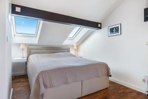a white bedroom with a bed and two windows at Haus Ostseesonne in Baabe