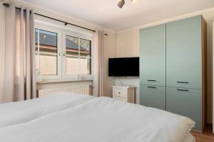 a bedroom with a white bed and a tv at Ferienhaus Jadeblick I I in Dangast