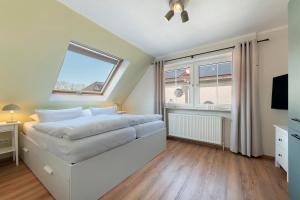 a bedroom with a bed and a tv and windows at Ferienhaus Jadeblick I I in Dangast