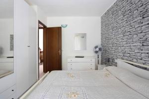 a bedroom with a white bed and a stone wall at Da Ercolino in Pitelli