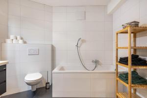 a bathroom with a tub and a toilet and a sink at Apartments Winder 1 in Lustenau +8 photos