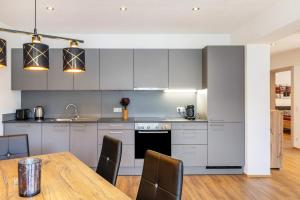 a kitchen with white cabinets and a wooden table at Apartments Winder 1 in Lustenau