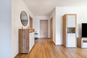 a kitchen with white walls and wooden floors and a mirror at Apartments Winder 1 in Lustenau