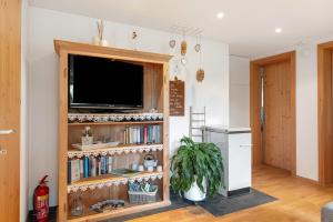 a living room with a tv and a book shelf at Haus Verdandi in Sibratsgfäll